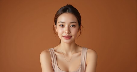 Minimalist skincare ad concept woman with luminous skin wears basic tanktop posing against warm terracotta studio background