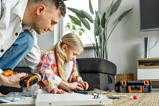 Father and daughter assembling furniture together at home