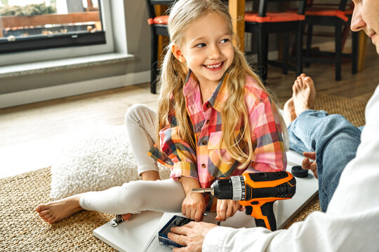 Father and daughter assembling furniture together at home, enjoying quality time and teamwork