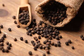 black pepper in a burlap sack on wooden bowl. Pepper, which has the Latin name Piper nigrum, is a...