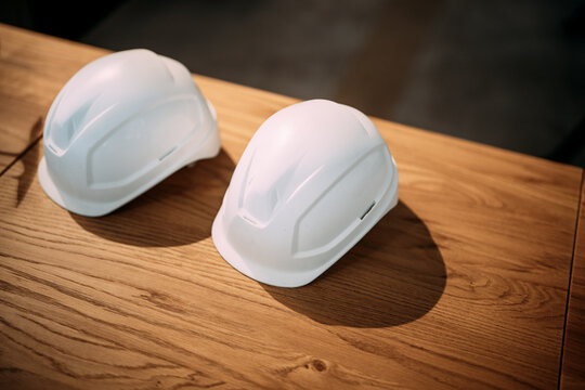 Two white hard hats on a wooden table indoors representing safety and teamwork in engineering