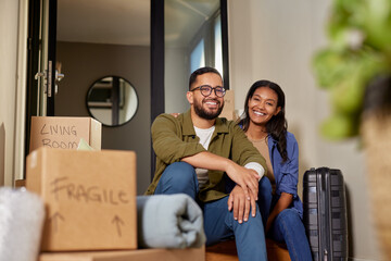 Portrait of happy mixed race couple relaxing after moving home