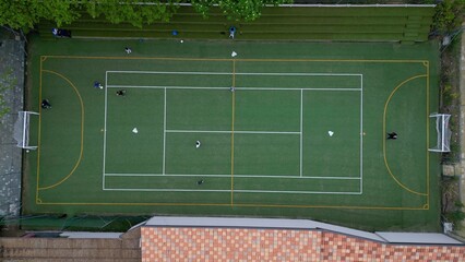Children playing five-a-side football and having fun playing an after-school football match - fun and sports during childhood - drone footage of a football sports centre
