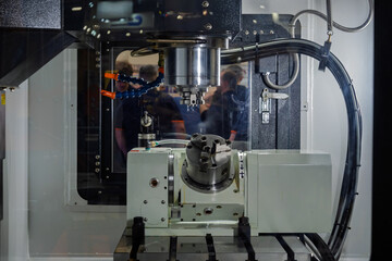 Metalworking Machine With a Part Being Machined Under the Supervision of Engineers in Safety Glasses