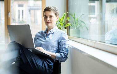 Businesswoman working on a laptop in a modern office setting