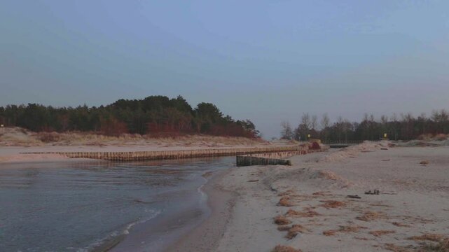 Peaceful footage of the Jamno Canal outlet into the Baltic Sea in Łazy. Filmed in winter near the storm barrier, with calm waves and no visible frost or snowfall.