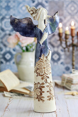 Postcard motif with blue angel figurine on the table.
