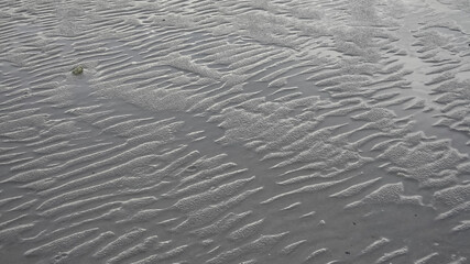 Wet sand with wave natural patterns.