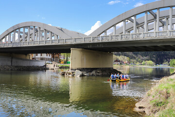 SZCZAWNICA, POLAND - APRIL 19, 2025: Tourists on a pontoon float down the river under the bridge.