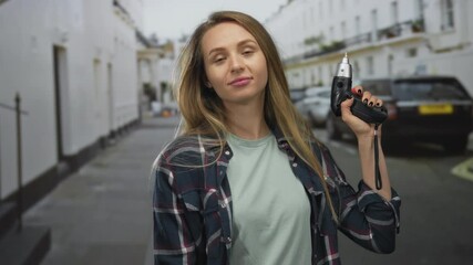 Woman laughing with power drill on city street in casual attire symbolizes confidence and empowerment. - Powered by Adobe