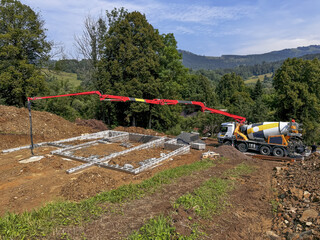 A concrete pump services a construction site amid lush greenery, showcasing the machinery and...