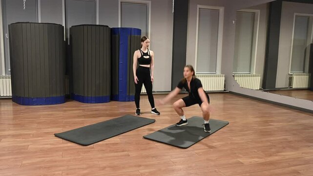 Caucasian woman doing burpees during personal training at fitness center. 