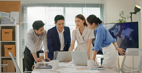 Multicultural business team gathered around laptop in modern office, focused on analyzing data, reviewing project strategy, collaborating on decision making with professional teamwork. Dolly zoom in.