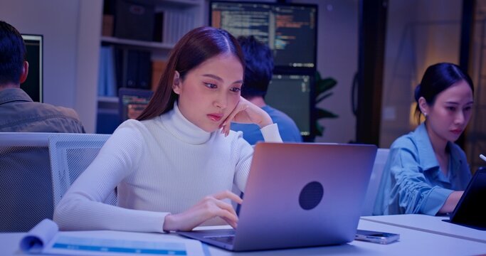 Diverse AI engineers working late in high-tech office, coding algorithms, analyzing data, and building intelligent systems. Focused teamwork and innovation drive future-ready software development.