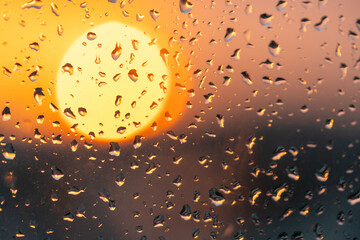 Raindrops on the window against the background of the setting sun. Background with glass and drip texture.