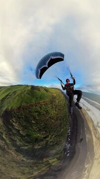 Extreme paragliding pilot soaring in the New Zealand beach at sunset. Adventure concept