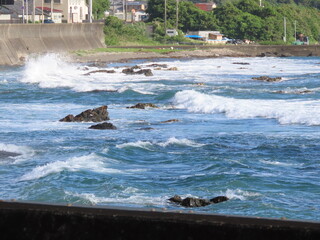 海が荒れて海岸に強い波が押し寄せて白波ができた景色