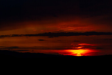The sun disappears behind the hills, casting the last crimson glow over a darkened land. A poetic ending to the day