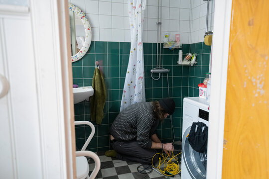 Man repairing drainage while kneeling in bathroom at home
