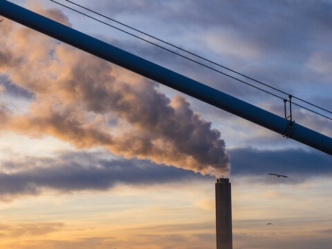 Smoke emitting from chimney under cloudy sky