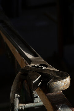 Close-up of adjustable wrench kept on wood in dark room