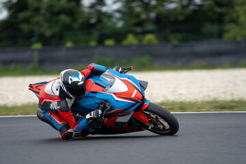 Blue-orange sports motorcycle leaning in the corner at a circuit. - obrazy, fototapety, plakaty