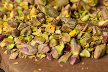 pistachios without shells, cut into pieces on a board, closeup