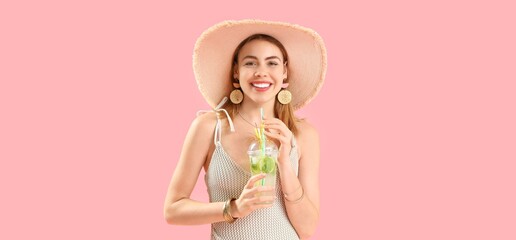 Beautiful happy woman in swimsuit holding tasty mojito on pink background