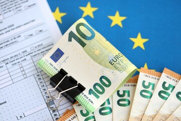 European euro currency money notes bunch on tax form and European union blue flag close up