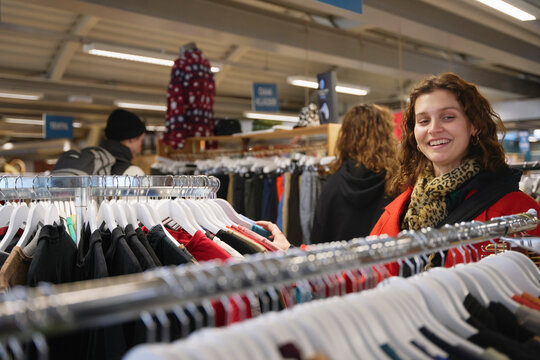 Happy woman looking at clothes in rack at store