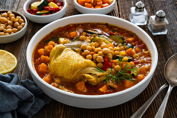 Fresh vegetable soup with lentil, chickpea and chicken on wooden table	