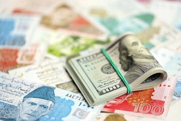 Stack of US dollar bills lies on big amount of Pakistan rupees banknotes close up