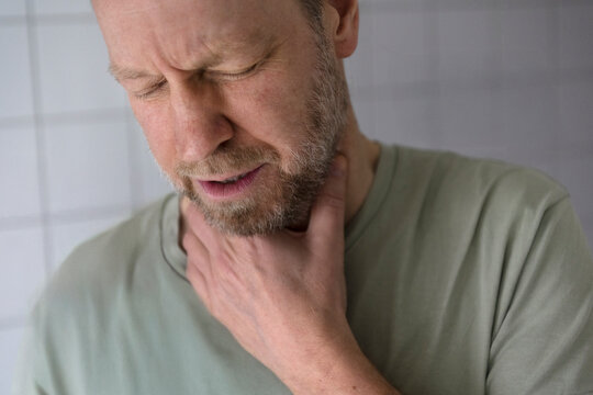 Man with eyes closed having throat pain