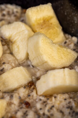 banana in oatmeal porridge, boiled oatmeal porridge with chia seeds, berries and fresh banana, close up
