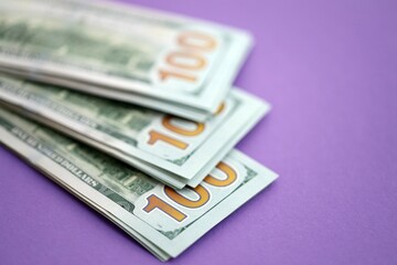 Big amount of United States hundred dollar bills on purple background