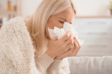 Ill mature woman with tissues at home, closeup