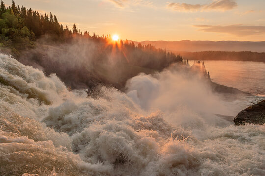Blurred motion of water splashing near trees at sunset