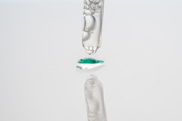 Dropper with collagen and hyaluronic acid serum on a white background with reflection. A drop of lotion for the skin of the face on the glass. Close-up, macro photography. Space for text