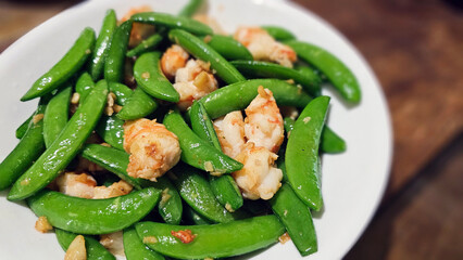 Enjoying a delicious stir-fried seafood dish with shrimp and crispy green sweet peas — a...
