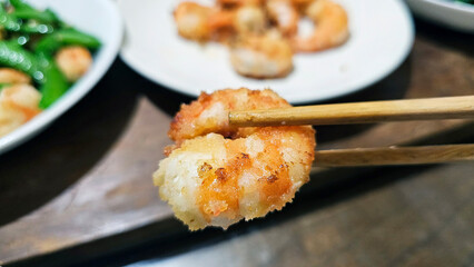 Enjoying eating delicious crispy garlic-fried shrimp and juicy stir-fried shrimp with fresh seafood with chopsticks— traditional Taiwanese stir-fry restaurant cuisine