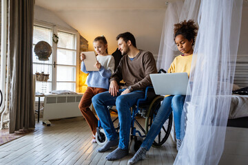 Father with disability in wheelchair uses digital devices with his interracial daughters to have fun
