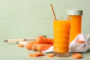 Glass and sports bottle of fresh carrot juice on green wooden table