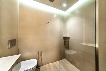 Contemporary bathroom with walk-in shower, wall-mounted toilet, and warm lighting. Clean lines and neutral tones define stylish, functional design.