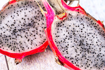 Dragon fruit or Pitahaya is a fruit cut in half on a wooden gray background. Close-up.