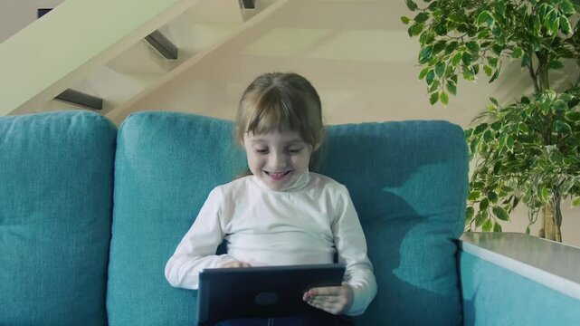 Funny Curious Cute Preschool Girl Using Digital Tablet Technology Device Small Child Hold Pad Computer Play Game At Home. Children Tech Addiction Concept