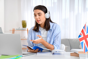 Young woman in headphones learning English language online at home © Pixel-Shot