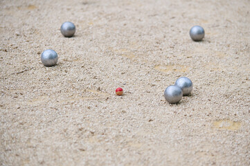 Petanque balls scattered on a gravel court around a small target ball cochonnet during a game. Outdoor sports scene, focused on strategy and precision