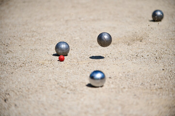 Petanque balls scattered on a gravel court around a small target ball cochonnet during a game. Outdoor sports scene, focused on strategy and precision