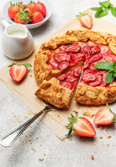 Delicious homemade strawberry galette with almond petals baking on parchment paper