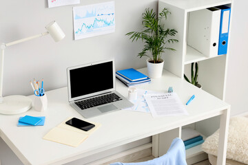 Workplace with blank laptop and plant in light office